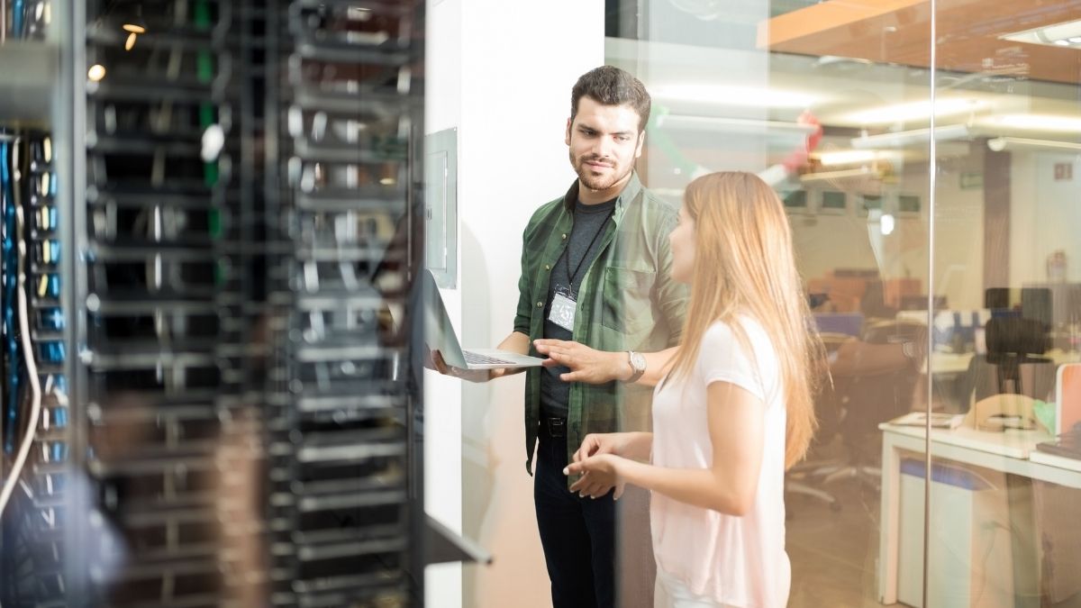 man and woman looking at laptop in data centre