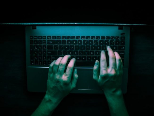 hands using laptop in low lighting
