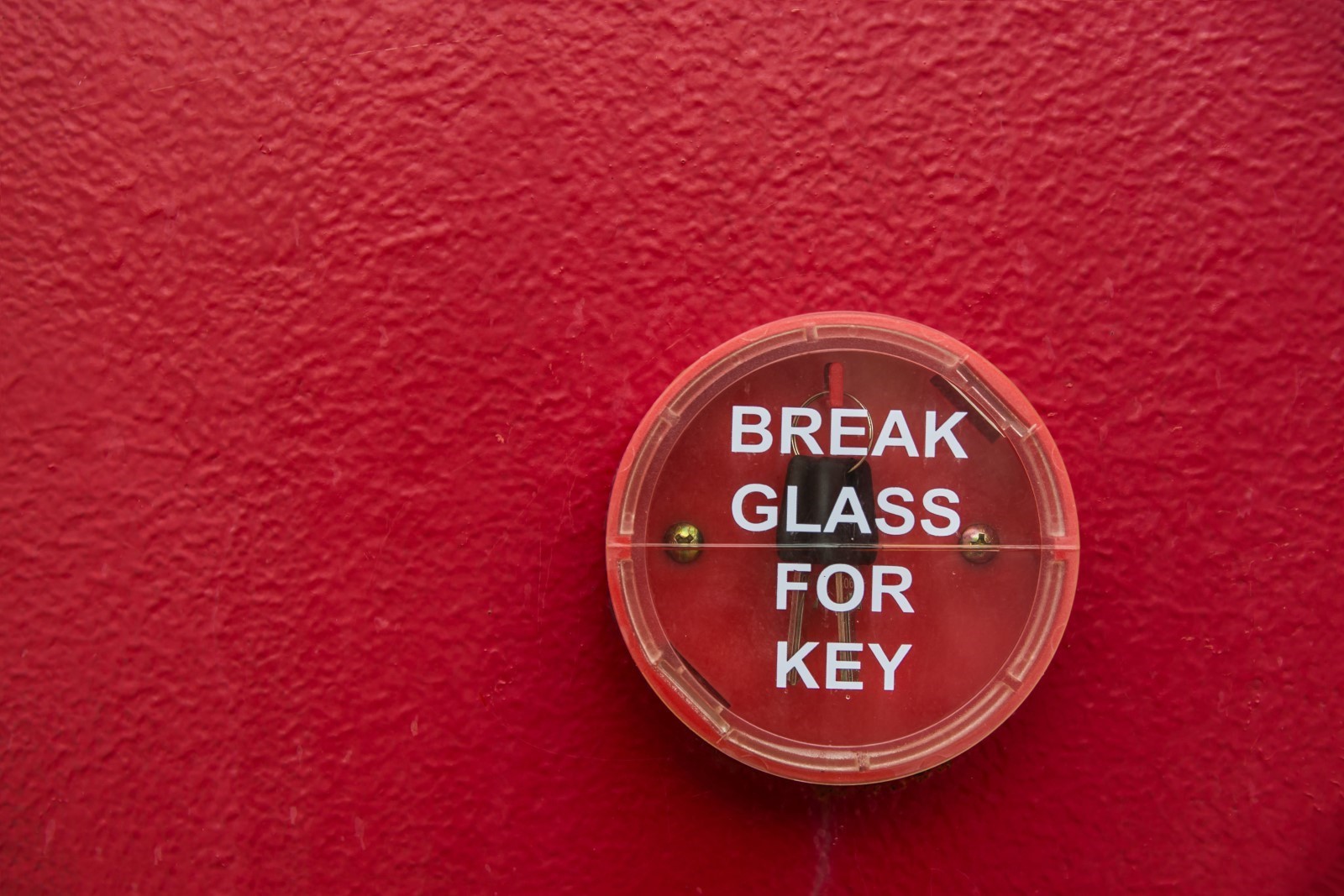 break glass for key sign on a red wall