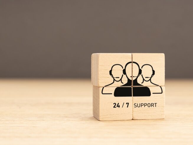 wooden blocks with an illustration of three IT support technicians and the words 24/7 support